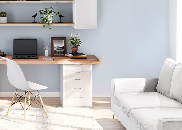 ライトウッドのデスクにノートパソコンと白いオフィスチェア、木製の壁掛け棚、白いソファが置かれたスタイリッシュなホームオフィス。